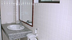 A bathroom with a white toilet, a sink with a mirror above it, and tiled walls. - Tam Coc Victoria Hotel (Nam Hoa Lu)