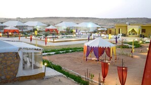 Un complexe hôtelier situé dans le désert, comprenant plusieurs tentes et une piscine.