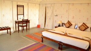 Une chambre à coucher avec un grand lit, un bureau, une chaise, un miroir et une table de chevet avec une lampe.