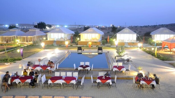 Un hôtel doté d’espaces de restauration en plein air, d’une piscine et de tentes installées à l’arrière-plan.