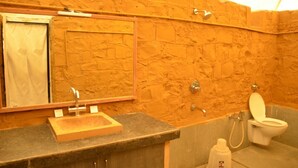 Une salle de bain avec un mur en pierre, un lavabo en bois, un miroir, des toilettes et une douche.