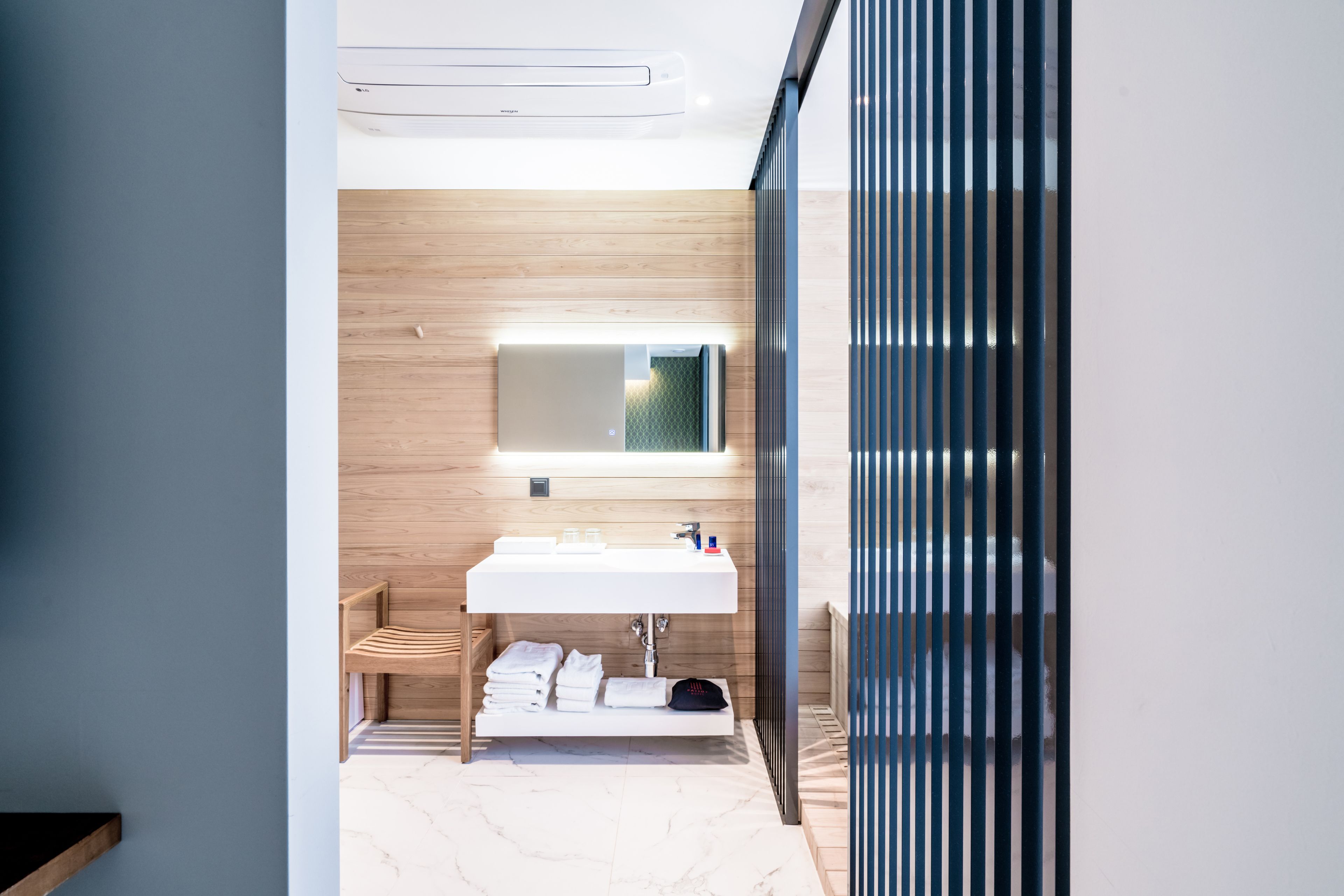 Een moderne badkamer met een houten wastafelmeubel, een grote spiegel en een handdoekrek.