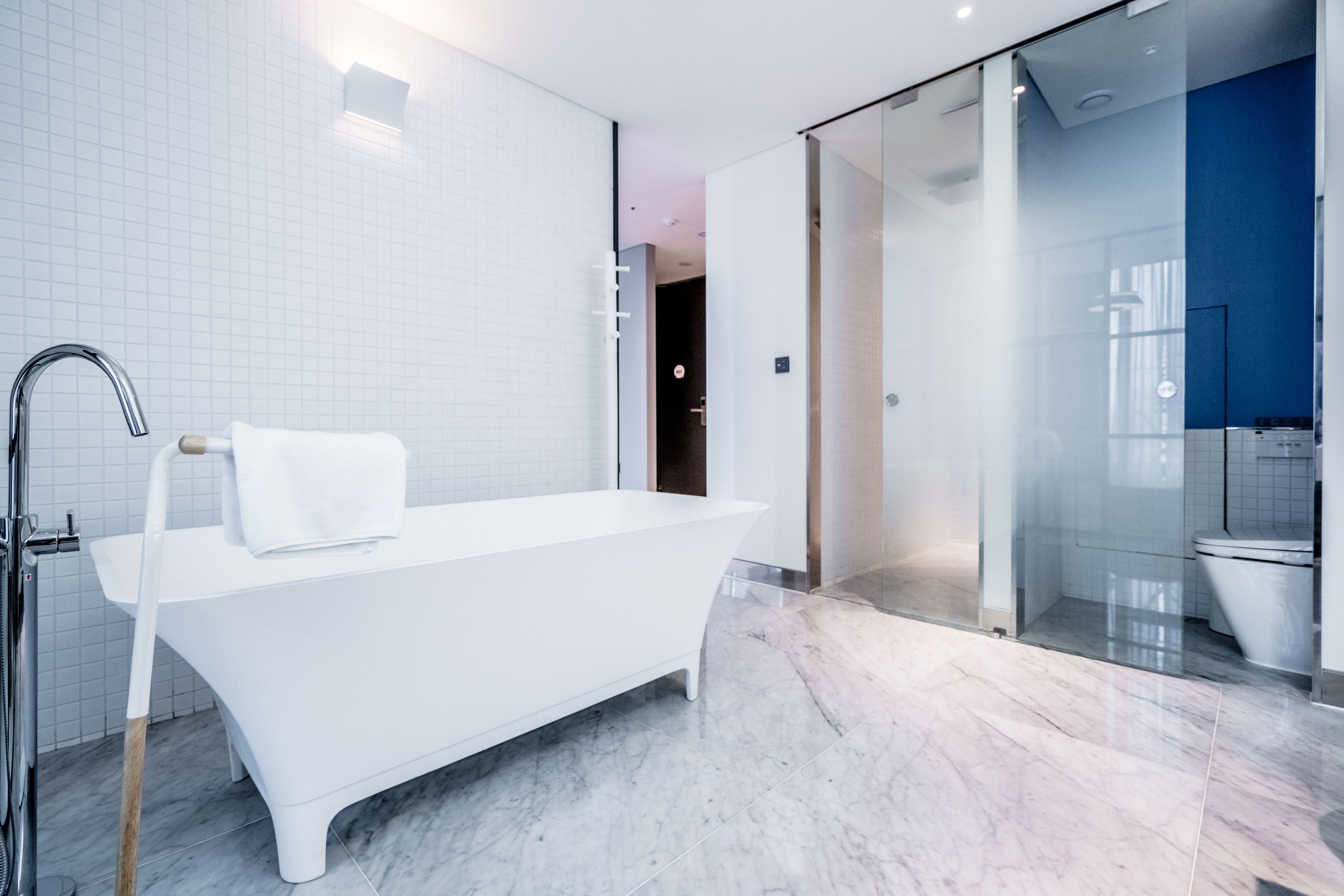 Un baño moderno con una bañera independiente, un box de ducha de vidrio y suelo de mármol.