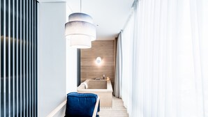 A modern bathroom with a bathtub, a towel rack, and a wooden floor. - Patio7 Hotel (Seoul)