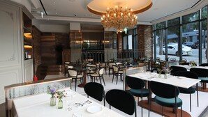 A restaurant with multiple tables and chairs, a chandelier, and large windows. - Patio7 Hotel (Seoul)