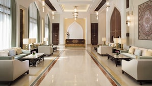 Spaziosa hall con una reception centrale, affiancata da aree relax e lampadari moderni.