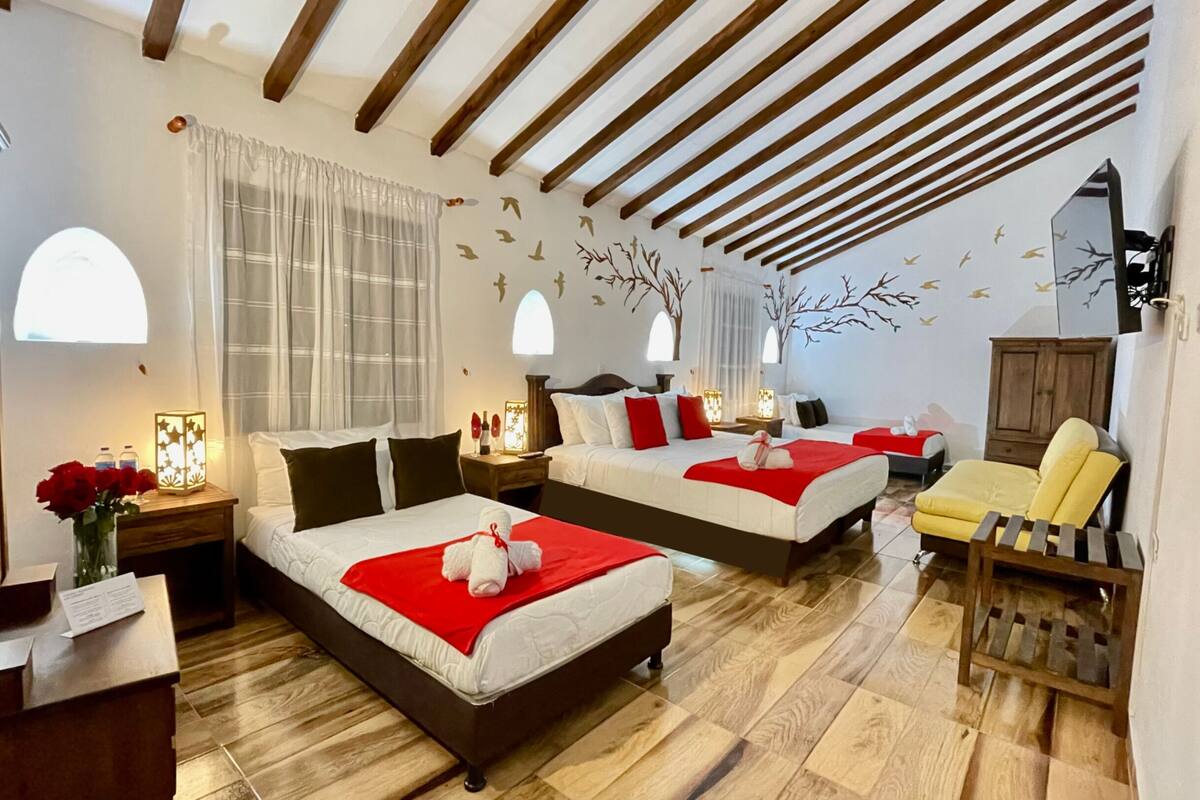 A hotel room with two beds, a wooden floor, a wooden chair, and a wall mural.