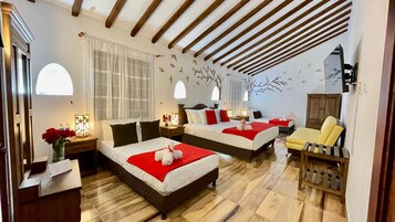 Habitación de hotel con dos camas, suelo de madera, una silla de madera y un mural en la pared.