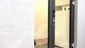 Una puerta corredera de vidrio moderna con marco negro, que da a una habitación con interior en tonos neutros y una zona de ducha visible.