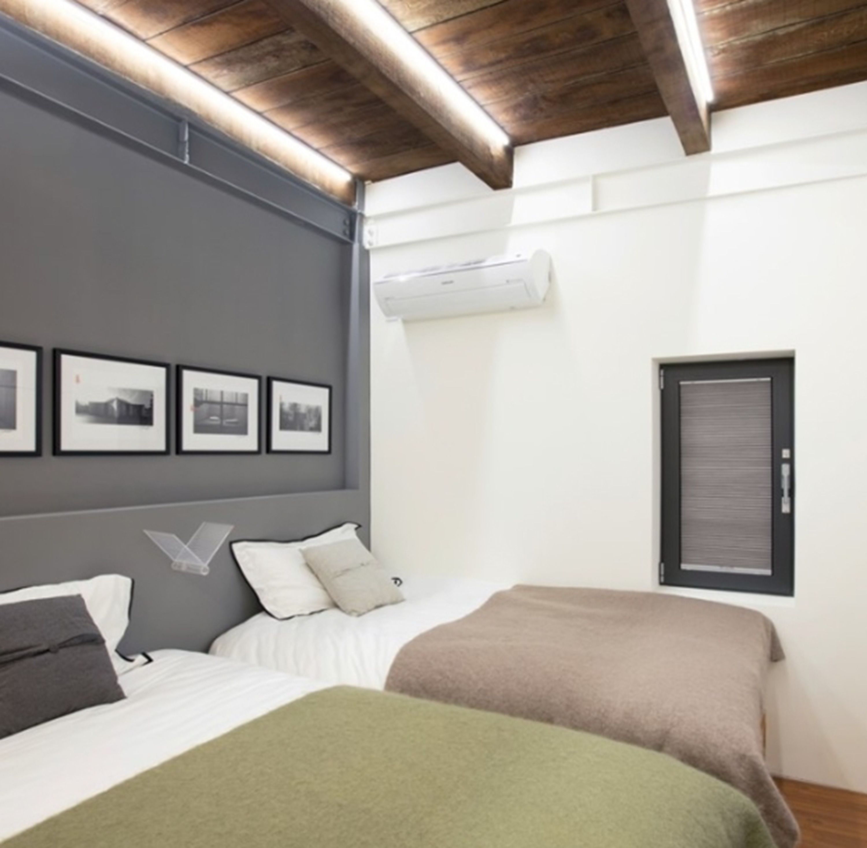A bedroom with a bed, a window, and a wall-mounted air conditioner.