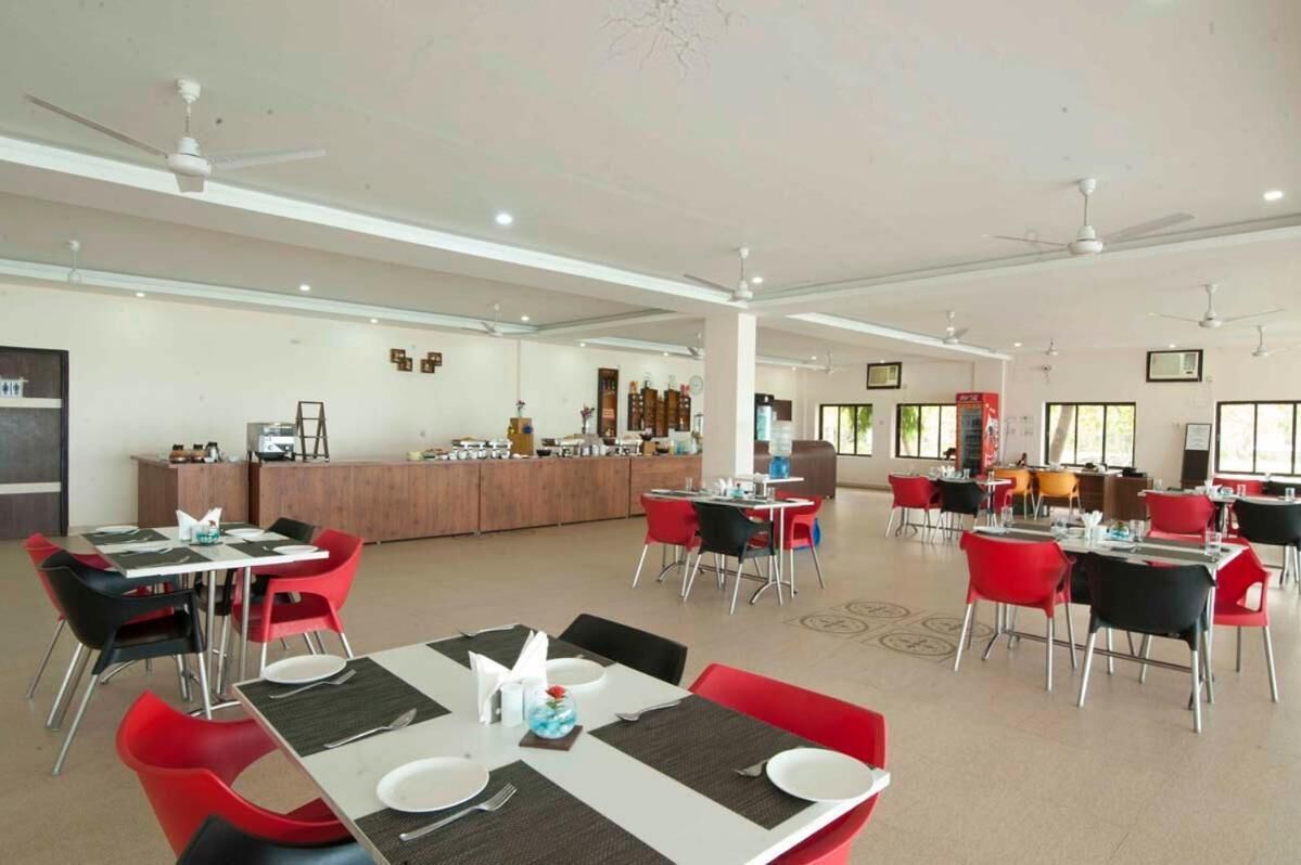 Un vaste espace dédié à la salle à manger, avec de nombreuses tables et chaises, un comptoir central et des ventilateurs de plafond.