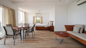 A hotel room with a dining area, a sofa, and a bed.