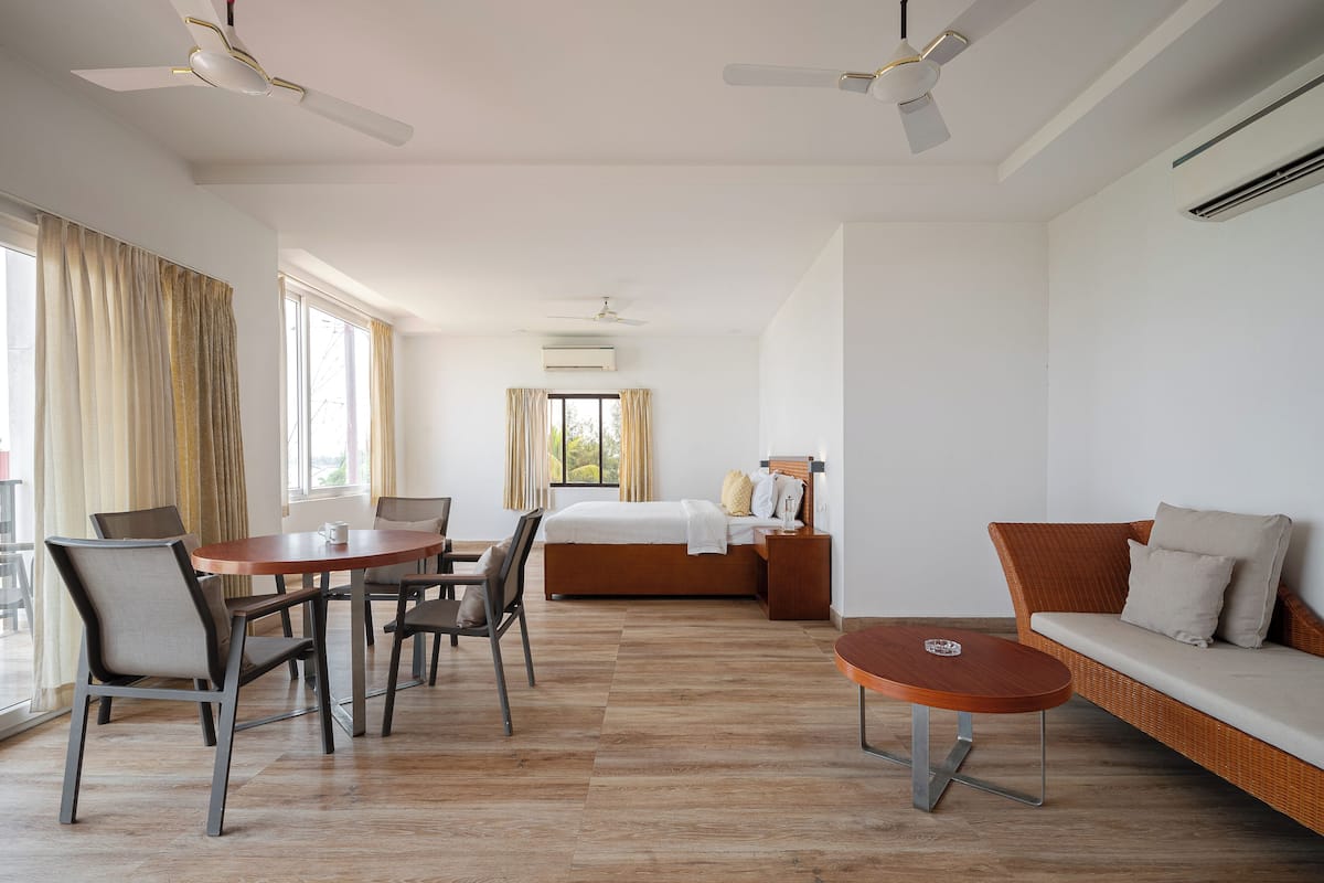 A hotel room with a dining area, a sofa, and a bed.