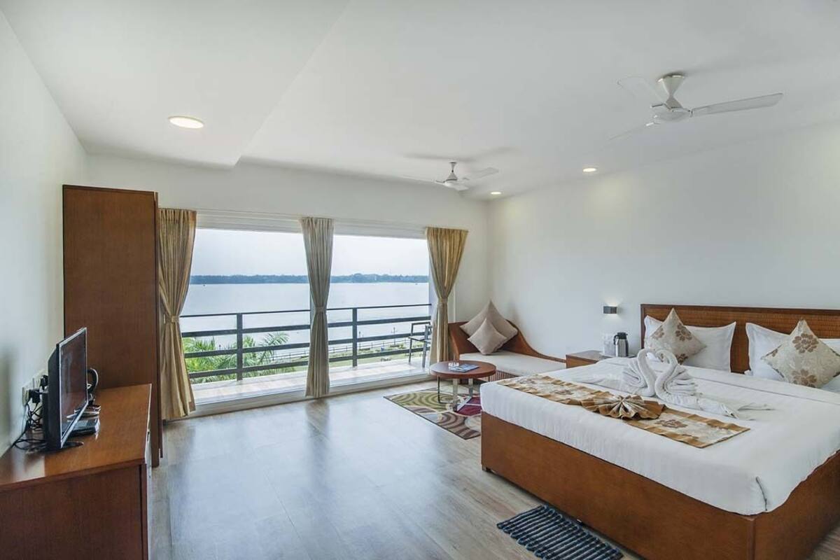 A spacious bedroom with a large bed, a desk, and a view of the sea.
