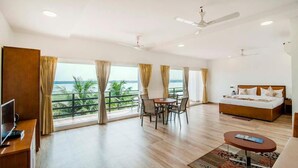A spacious room with a balcony, a bed, a TV, and a dining area.
