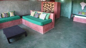 A room with a green sofa set, a black table, and a decorative panel. - Eagle Camp Mida Creek (Watamu)