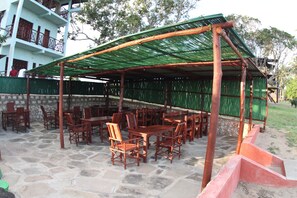Un patio al aire libre con mobiliario de madera y un toldo verde.