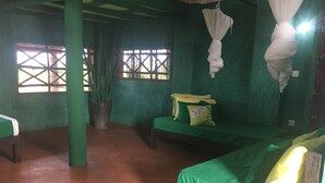 A room with green walls, a large potted plant, and two beds with green and yellow bedding. - Eagle Camp Mida Creek (Watamu)