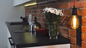 A kitchen with a black countertop, a vase with flowers, and a hanging light fixture. - Panda Apartments Grzybowska-Centrum (Warsaw)