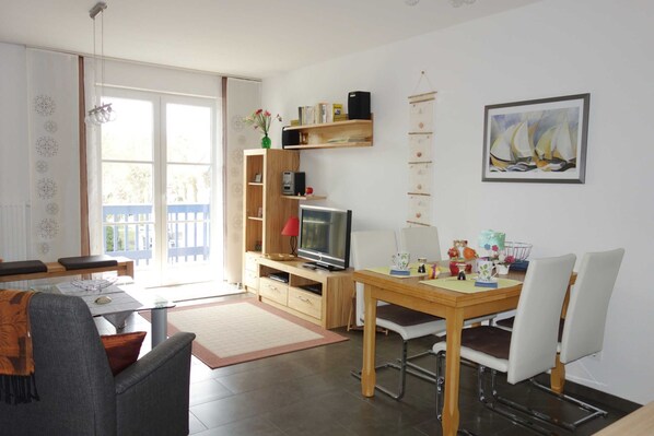 A modern living room with a dining area, a TV, and a bookshelf.