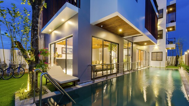 A modern building with a swimming pool, large windows, and outdoor seating. - Sun Paradise Villa (Da Nang)