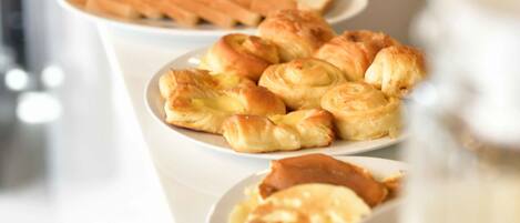 A breakfast buffet with pastries, bread, and a coffee pot.
