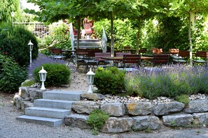 A garden patio with stone steps leading to a seating area, surrounded by lavender and greenery. - Landhotel-Restaurant Adler (Deggenhausertal)