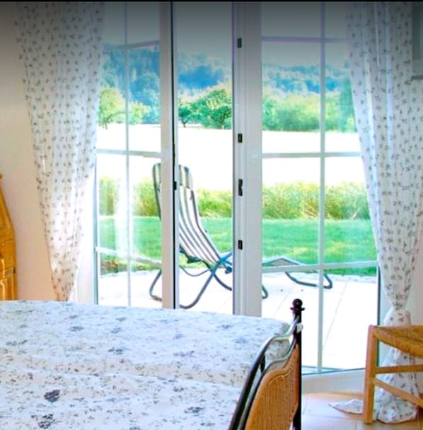 A bedroom with a bed, a chair, and a view of a garden through a sliding glass door. - Landhotel-Restaurant Adler (Deggenhausertal)