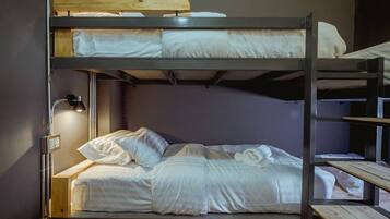Una cama litera con cabecera de madera, una lámpara de pared y un enchufe.