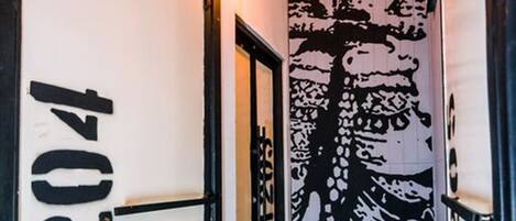 A hallway with a black and white mural on the wall, a black floor, and a door with the number "2014" on it.