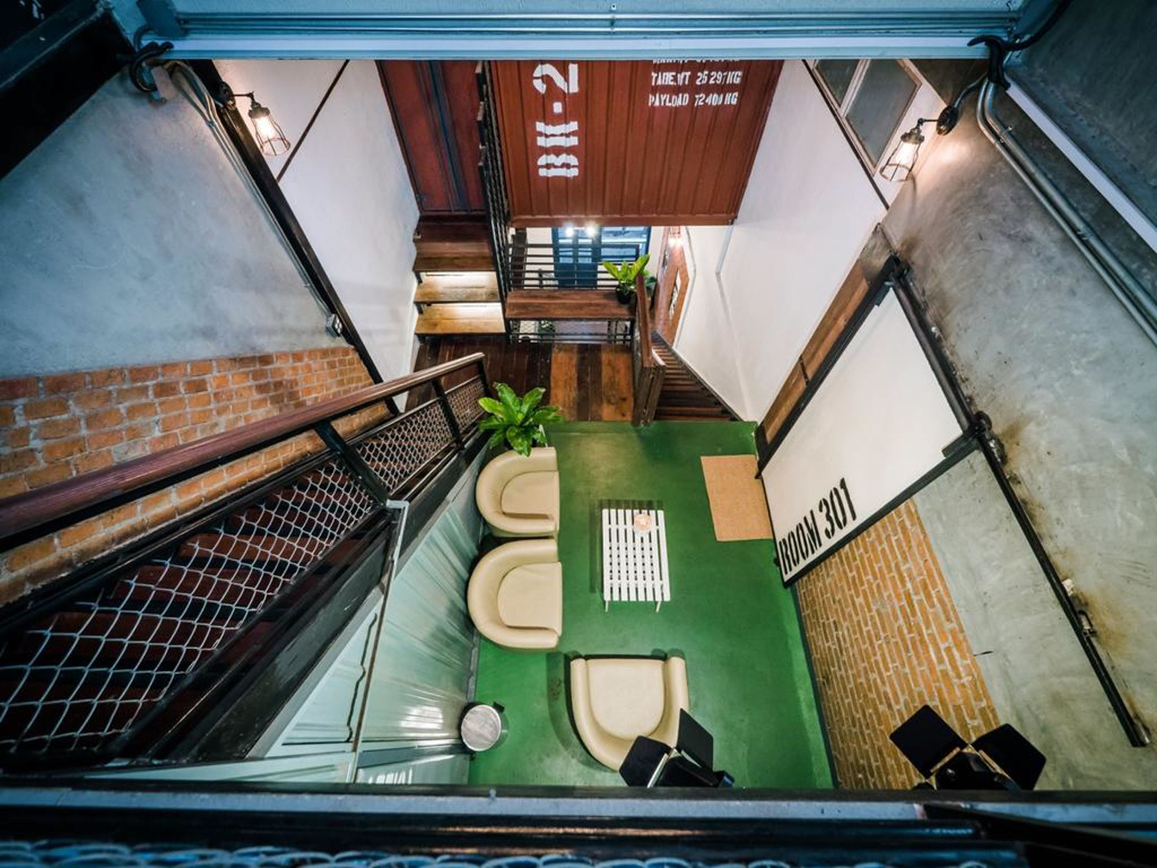 A modern interior with a green carpet, a seating area with chairs, a small table, and a sign indicating room 301.