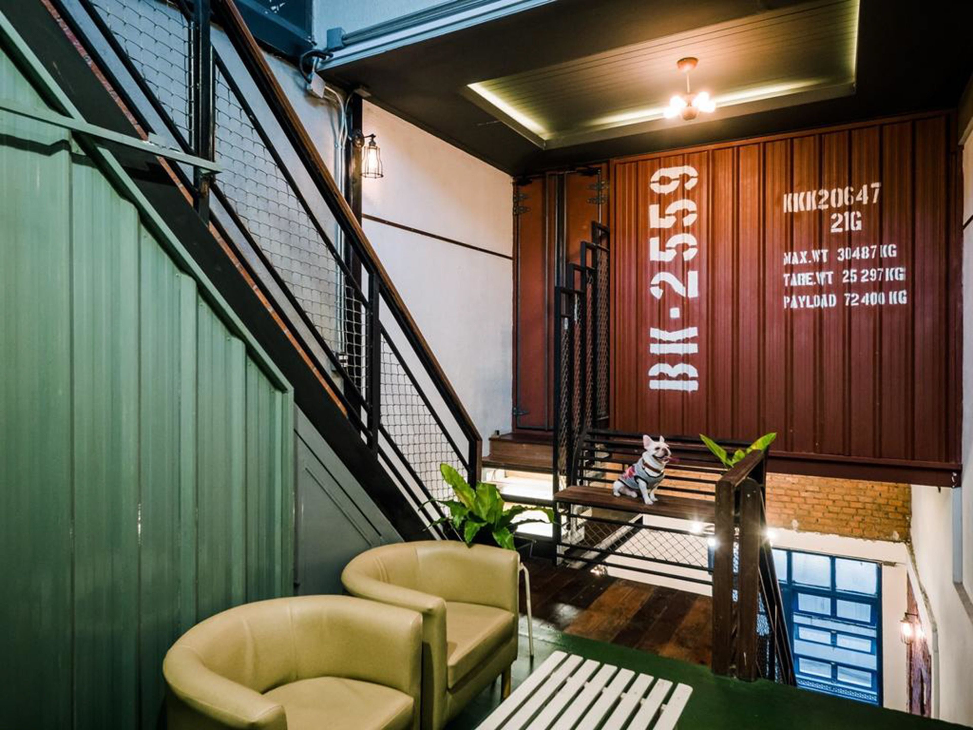 A modern interior with a staircase, a wooden wall with weight capacity information, and a dog sitting on a bench.