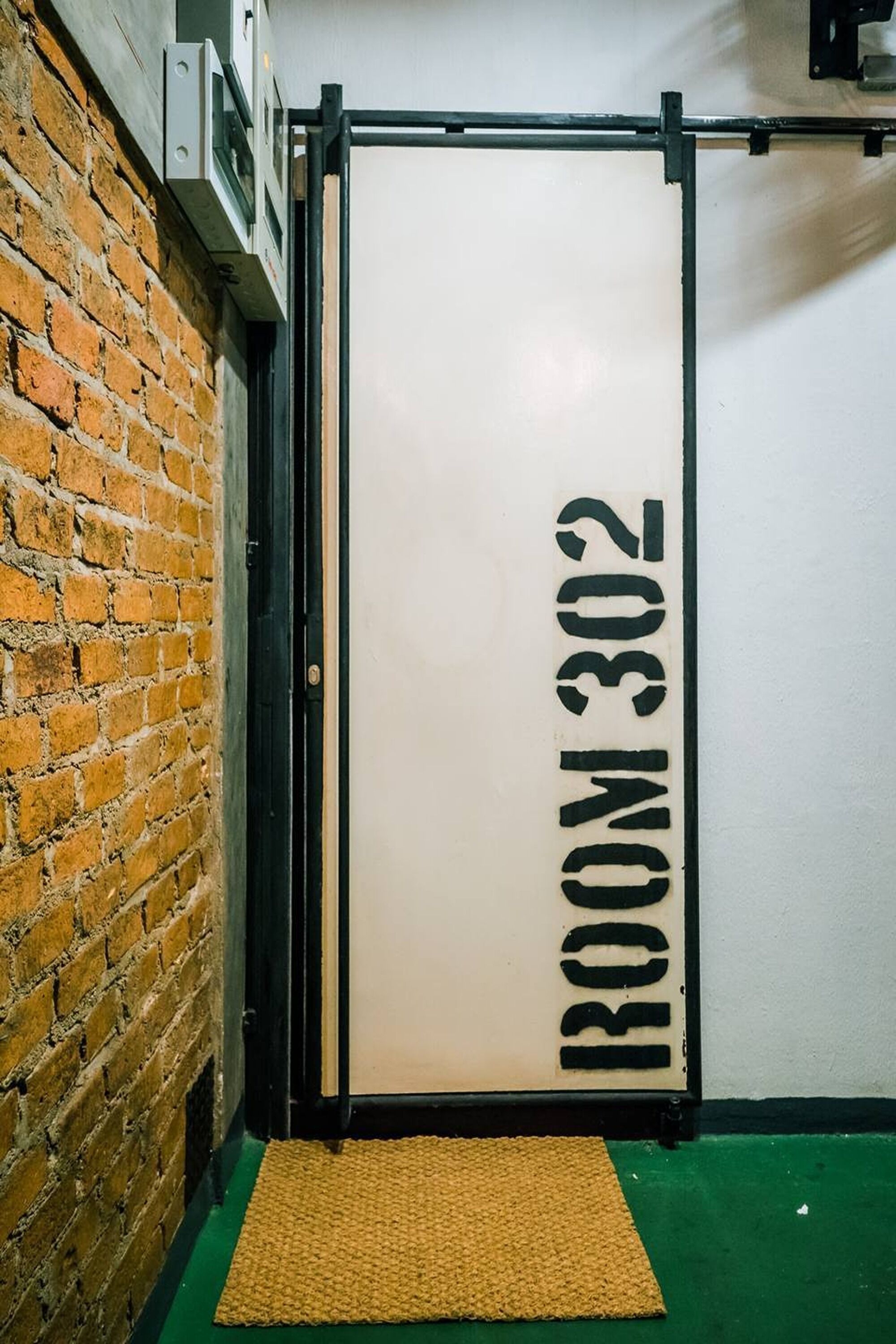 A room with a door labeled "ROOM 302" against a brick wall.