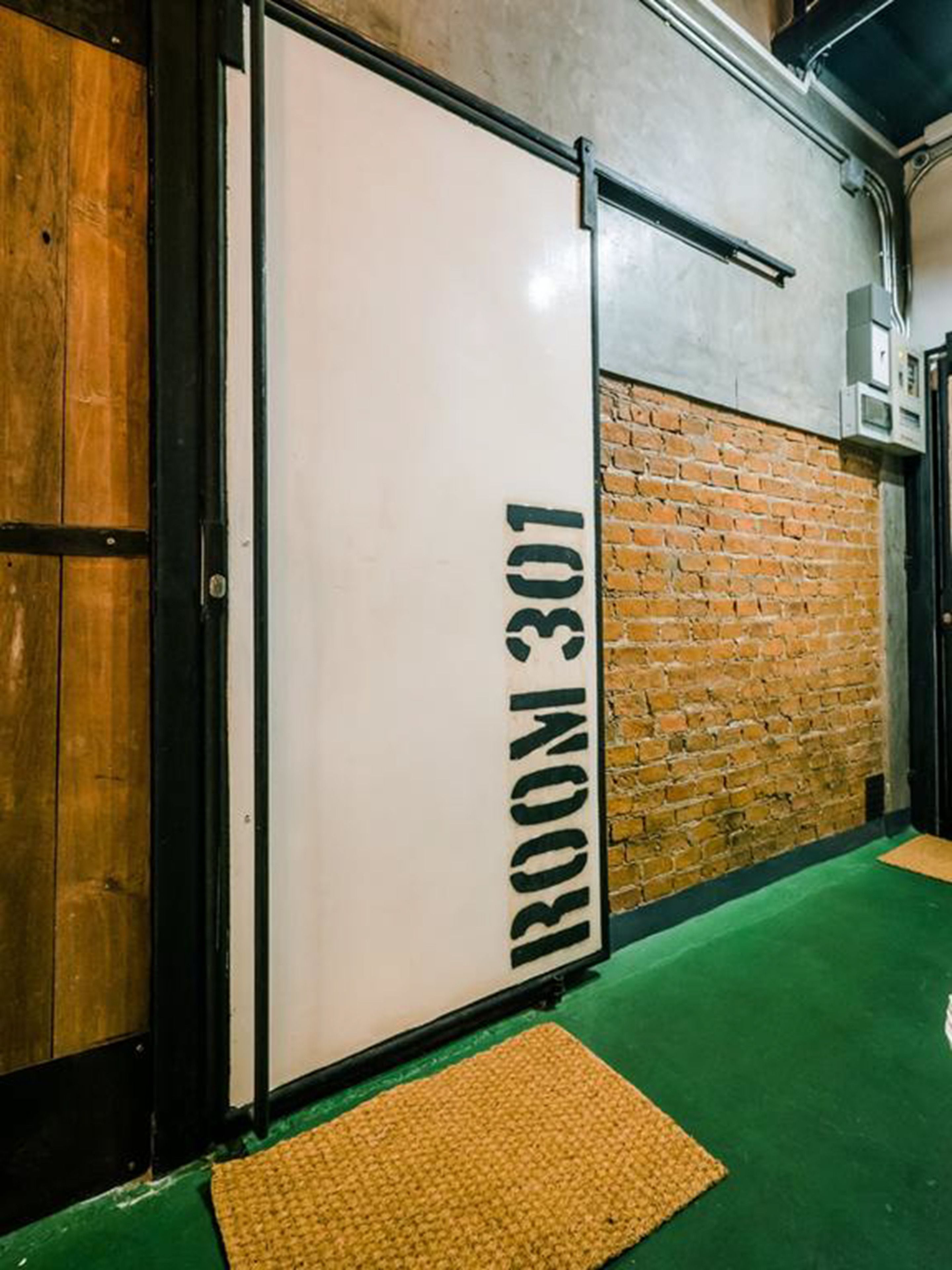 A room with a white door labeled "ROOM 301" against a brick wall.