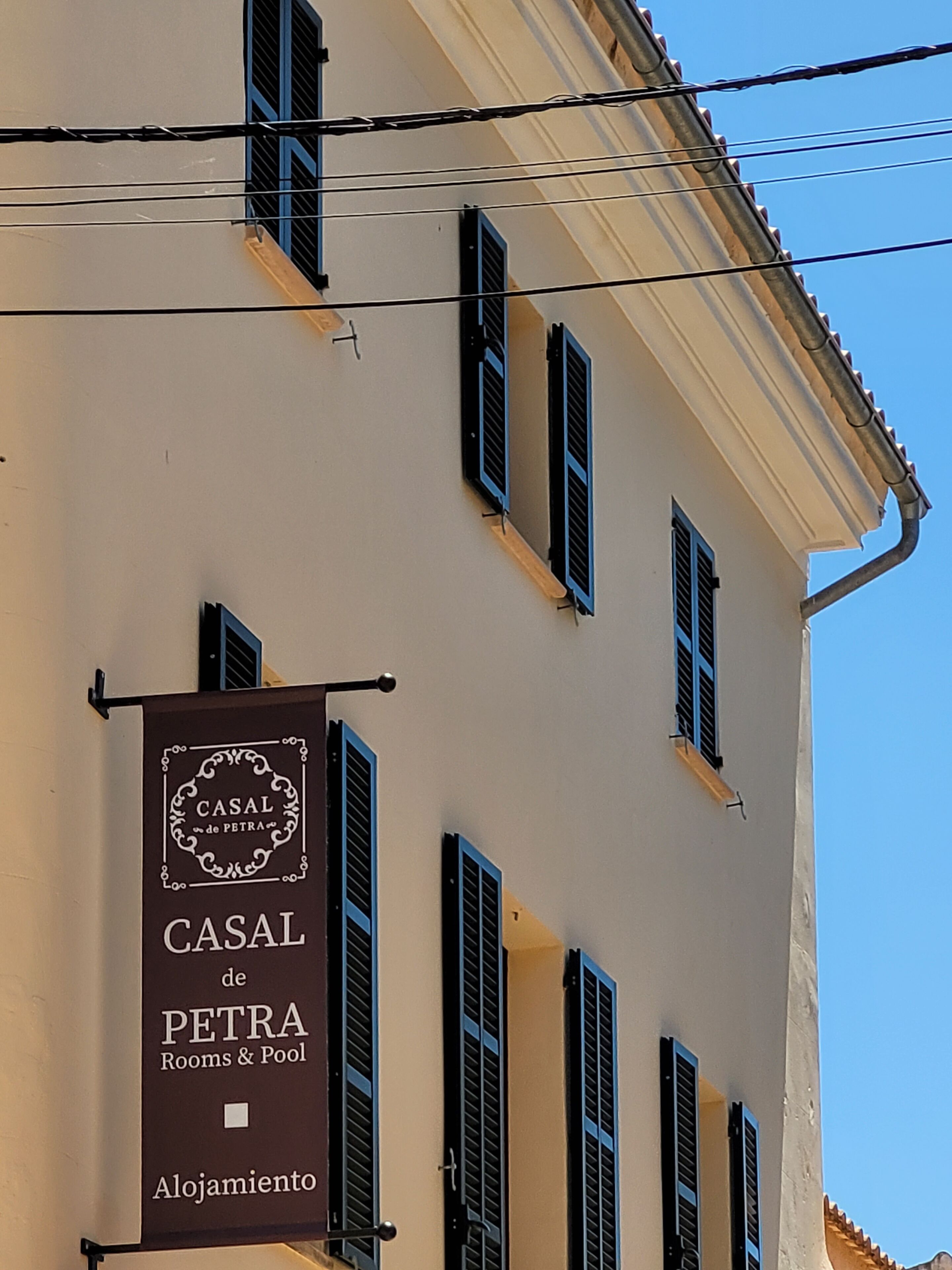 Un edificio con varias ventanas y un cartel que anuncia "CASAL de PETRA Rooms & Pool Alojamiento".