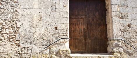 A stone building with a large wooden door and steps leading up to it.
