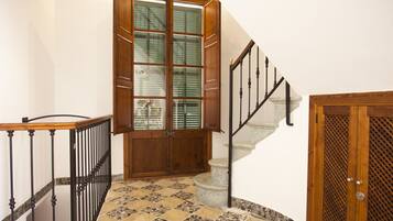 Una escalera con barandilla de madera y pared de piedra.