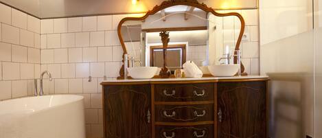Une salle de bain avec une baignoire îlot, un meuble-lavabo en bois doté de nombreux tiroirs et un grand miroir au-dessus du meuble-lavabo.