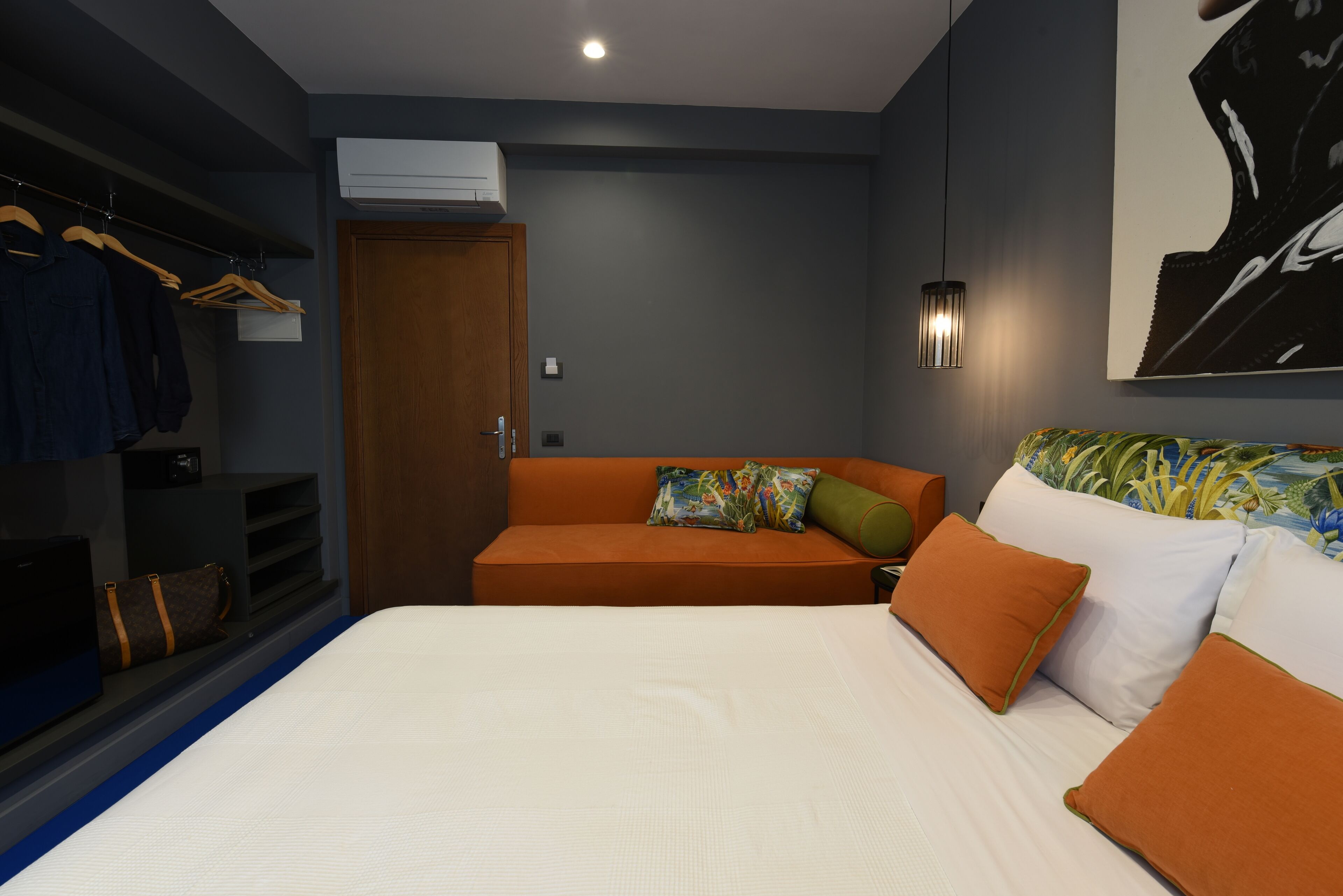 Een slaapkamer met een bed, een bank, een kledingkast en een airconditioning.
