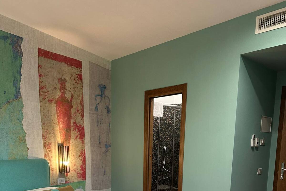 Un dormitorio moderno con una cama grande, una mesita y una puerta que da al baño.