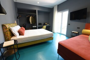 Een moderne slaapkamer met een bed, bureau, televisie en een groot raam.