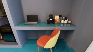 A modern workspace with a laptop, coffee maker, and snacks on a glass desk.
