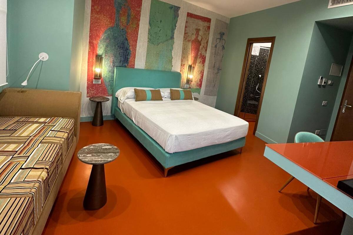 Un dormitorio moderno con cama, escritorio, silla y sofá.