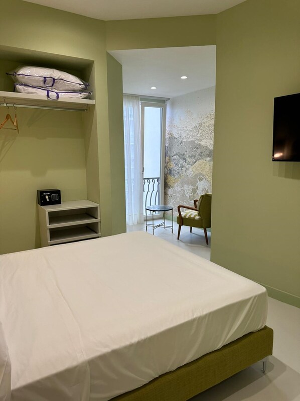 Een slaapkamer met een bed, een tafeltje, een stoel en een balkon met uitzicht.