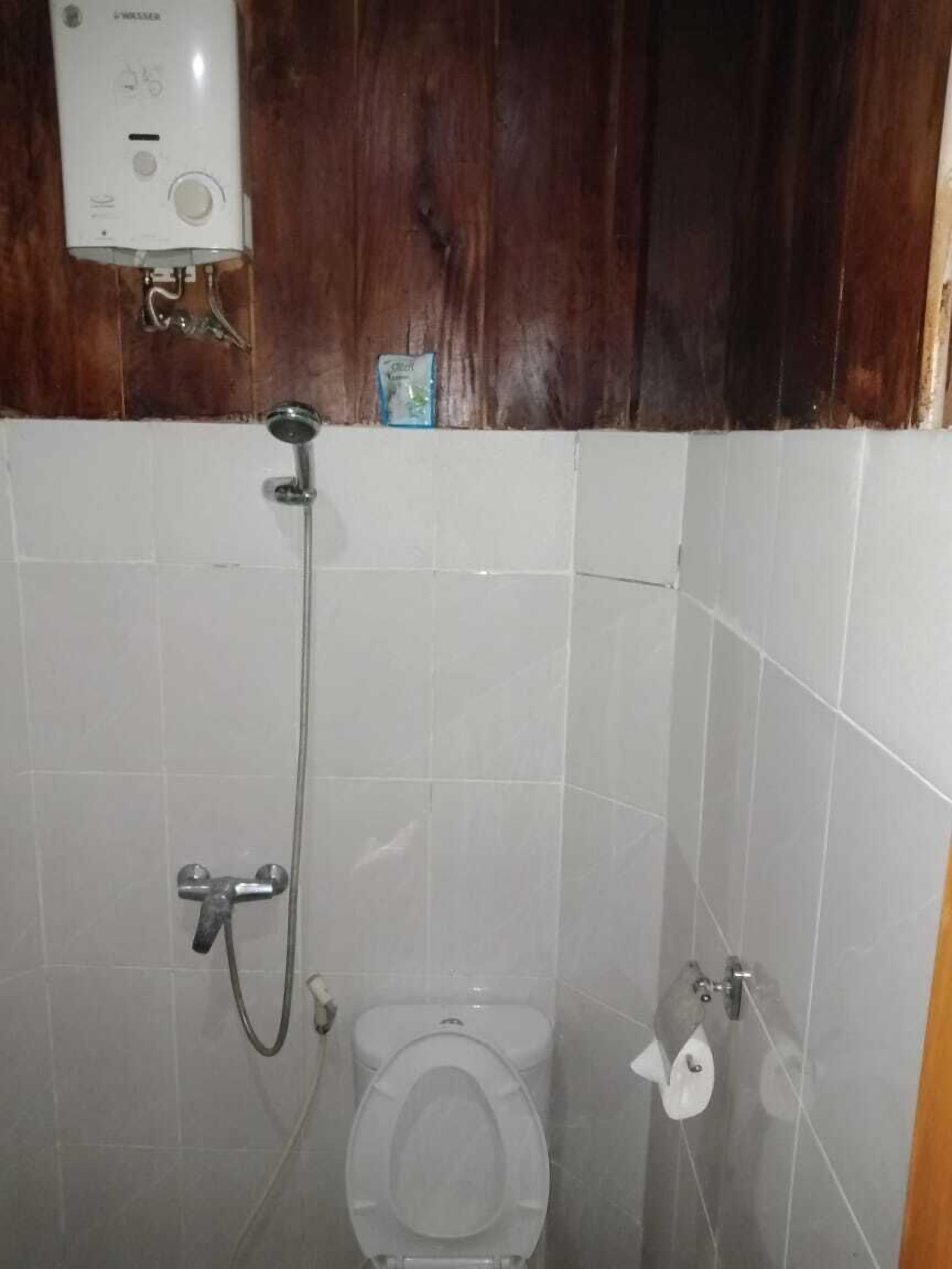 A small bathroom with a toilet, a shower, and a toilet paper holder.