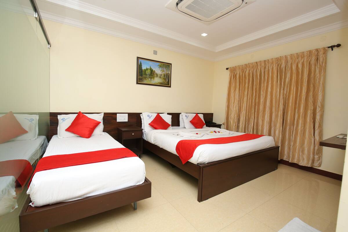 A hotel room with two beds, a painting on the wall, and a curtain.
