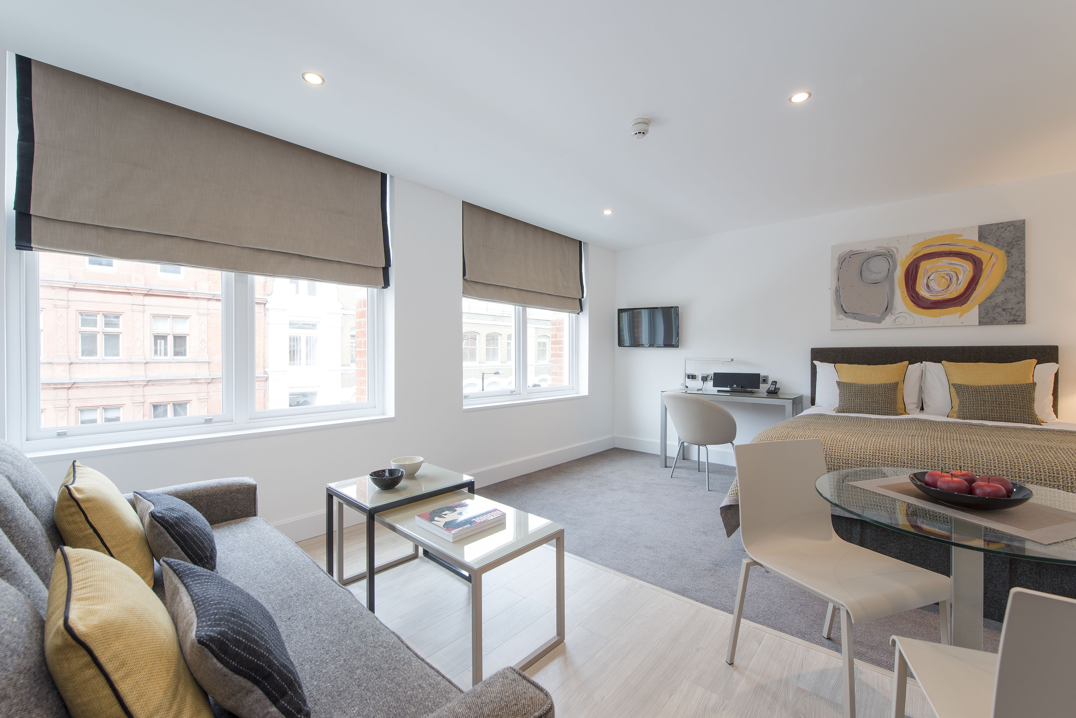 Una sala de estar moderna con un sofá, una mesa de centro de vidrio y una zona de comedor con mesa y sillas.