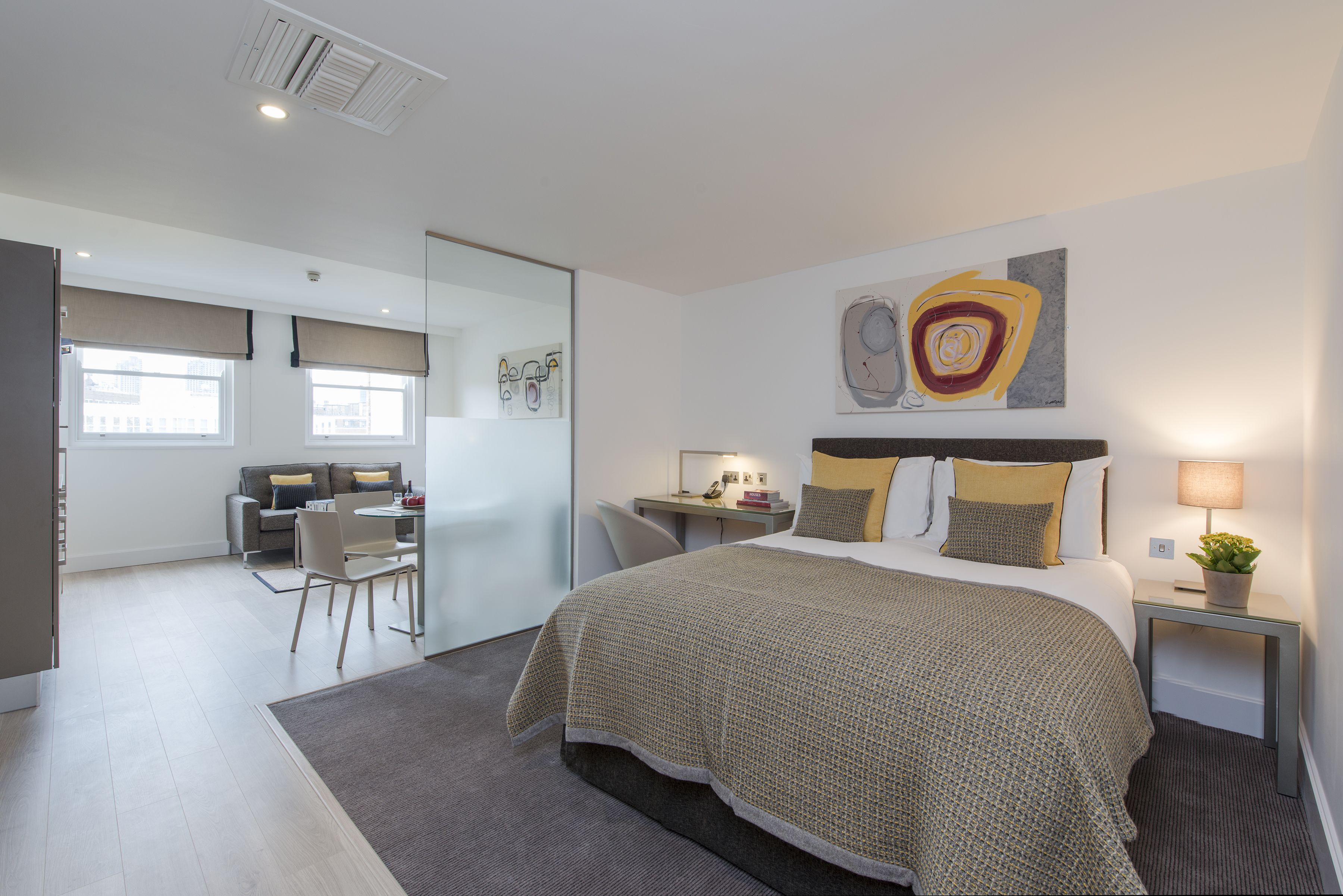 A modern hotel room with a large bed, a desk, and a seating area.
