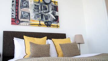 Hotellihuone, jossa on suuri sänky, sängynpääty ja taulu seinällä.