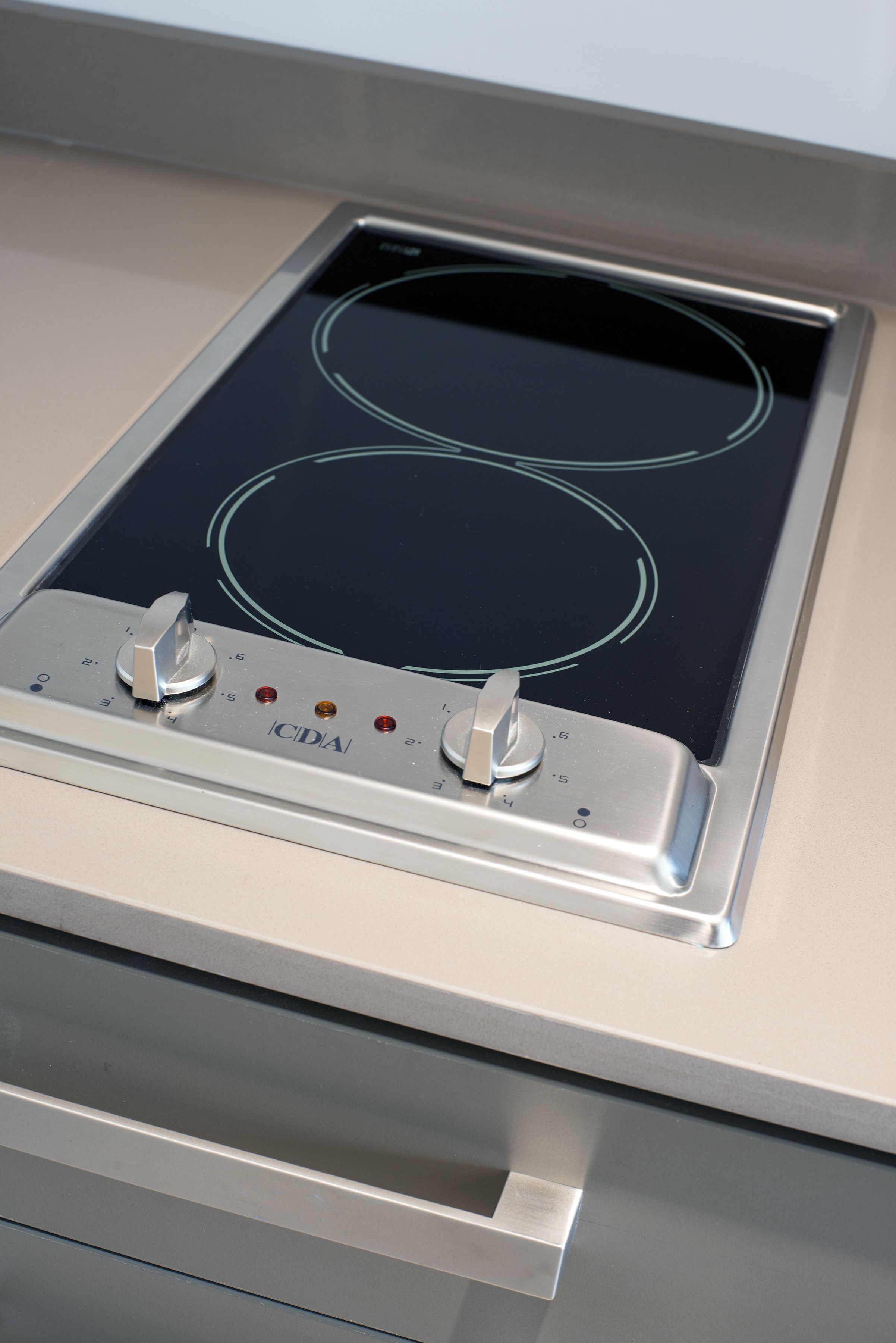 A kitchen with a built-in induction cooktop and a stainless steel oven.